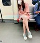 A woman wearing a face mask sitting on a subway train.