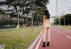 A naked woman walking down a street next to a tree.