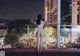 A naked woman standing on a balcony looking out at the city.