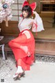 A woman in a red and white kimono sitting on a bench.