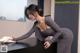 A woman in a gray dress cleaning a black table.