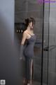 A woman in a gray dress standing in a shower.