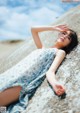 A woman laying on a rock on the beach.