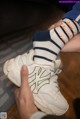 A person holding a pair of white sneakers with a New York Yankees logo.