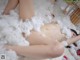 A naked woman laying on top of a pile of white cotton.