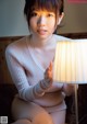 A woman sitting on a bed next to a lamp.