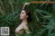 A naked woman standing in the middle of a lush green forest.