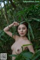 A naked asian woman posing in the jungle.