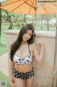 A woman in a polka dot bikini standing under an umbrella.