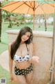 A woman in a polka dot bikini standing under an umbrella.