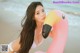 A woman in a white bikini holding a pink flamingo on the beach.