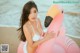 A woman in a white bikini sitting on an inflatable flamingo.