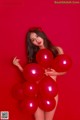 A woman holding a bunch of red balloons.