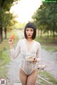 A woman in a white bodysuit holding a cupcake in her hand.