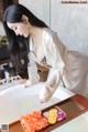 A woman in a white robe is washing her hands in a bathtub.