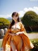 A woman in a yellow kimono posing for a picture.