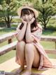 A woman in a pink dress and hat sitting on a wooden bench.