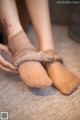 A woman tying up her bare feet with a bandage.