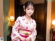 A woman in a pink and white kimono posing for a picture.