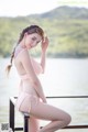 A woman in a pink bikini sitting on a dock.