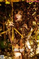 A woman in a white bikini is surrounded by leaves.