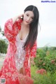 A woman in a red kimono posing in a field of flowers.