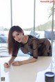 A woman in a black dress leaning over a white table.